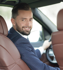 businessman sitting at the wheel of a car and looking at the camera