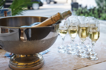 A bowl with cold champagne on the table with filled glasses.