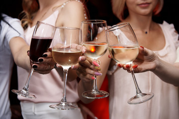 Сlinking glasses of cold wine in female hands.