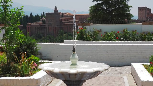 A view of a small fountain with the Alhambra behind