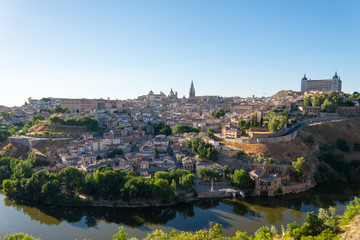 Fototapeta na wymiar Panoramic scenery of the ancient historical city of Toledo which located on the hill and enclosed by Tagus river during summer season in Toledo, Spain.