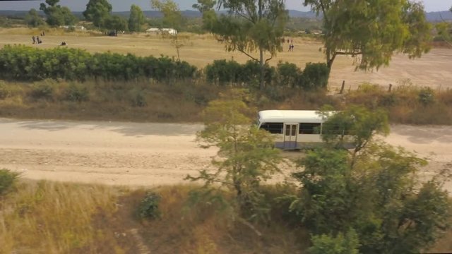 A Bus Driving Down a Dirt Road in Zimbabwe, Africa on a Sunny Day, Aerial View
