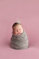Sleeping newborn girl on a pink background. Little princess with crown. Photoshoot for the newborn....