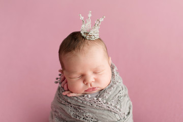 Sleeping newborn girl on a pink background. Little princess with crown. Photoshoot for the newborn....