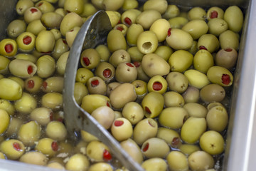 Close-up detail shot of red pepper filled green olive in metal box