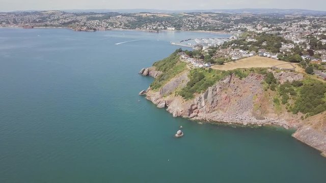 Aerial view of coastline in Torquay England. Panoramic view from the sky of beach town in southwest England. Blue ocean water, cliffs, and amazing landscape is visible.