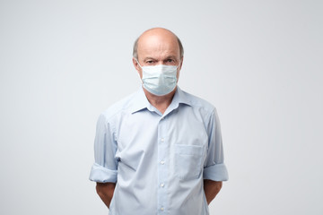 portrait of serious man in special medic mask. He is looking serious. Mature experienced doctor.