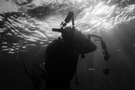 Silhouette of an underwater photographer diving in the waves at the surface of the Red Sea in Egypt