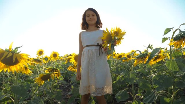 Happy little girl running happy free across the field with sunflowers. slow motion video. smelling big sunflower on summer field. Delight of a pleasant smell. Summer holiday. concept happiness