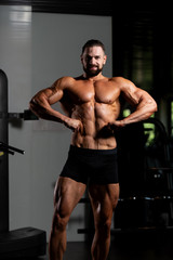 Fototapeta na wymiar Handsome Muscular Man Flexing Muscles In Gym