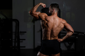 Obraz na płótnie Canvas Biceps Pose Of A Young Man In Gym