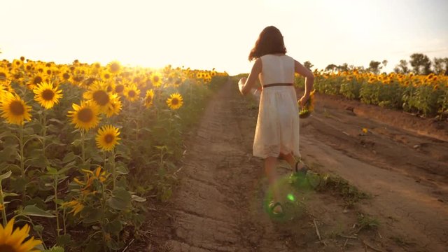 little girl running across the field with sunflowers at sunset. slow motion video. girl runner in the field at sunset sunflowers. girl sunlight runs the concept of lifestyle sunflowers