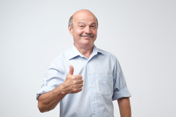 Handsome, bald man with his thumb up in sign of optimism on white background