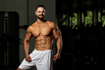 Fototapeta na wymiar Muscular Man In Sports Outfit In Fitness Center