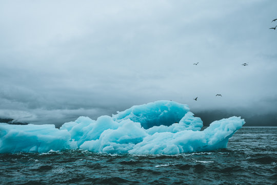 Blue iceberg in dark and rough waters