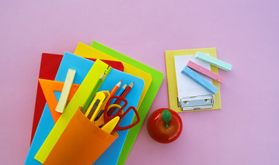 The schoolboy's accessories lie on a pink table. Textbooks and office.