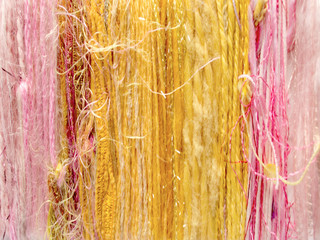Vertical striped background composed of varying colors and textures of yarns, creating color sequences from left to right.