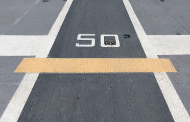 Number " 50 " on white and yellow runway. Takeoff runway and runway aircraft carrier on battleship. Public area.