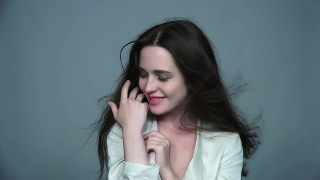 Video portrait of happy smiling young brunette woman portrait with green eyes and streaming hair in white fashion female jacket