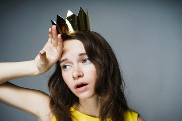 sad tired blue-eyed girl posing, wearing a golden crown