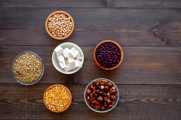 Vegan protein source. Legumes, nuts, cheese. Raw beans, chickpeas, lentil, almond, hazelnut on dark wooden background top view copy space