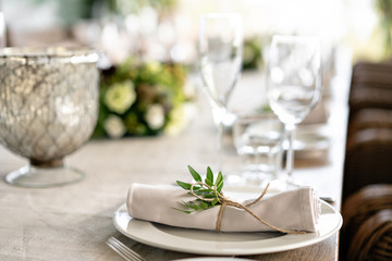 Neatly twisted into a tube dining room napkin decorated with a sprig of pistachio. Wedding Banquet or gala dinner. The chairs and table for guests, served with cutlery and crockery. party on terrace