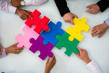 Group Of Businesspeople Solving Jigsaw Puzzle - obrazy, fototapety, plakaty