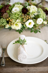 Neatly twisted into a tube dining room napkin decorated with a sprig of pistachio. Wedding Banquet or gala dinner. The chairs and table for guests, served with cutlery and crockery. party on terrace