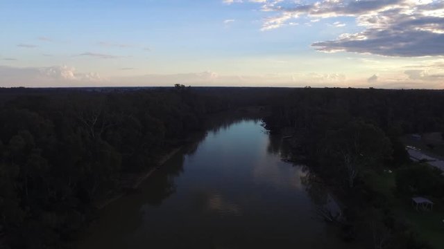 Drone panning down over the Murray River during sunset, blue sky. Wide shot.