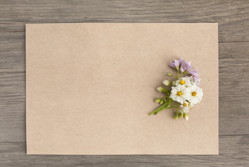 Potatoes white and purple flowers with craft blank paper on old grunge wooden background. Top view. Minimalistic mockup.