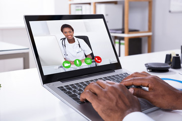 Person Video Conferencing With Female Doctor Through Laptop