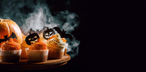 cupcake and pumpkin on a dark background. sweets for the celebration of Halloween.
