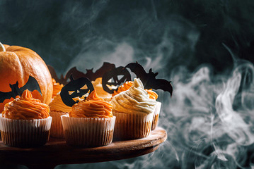 cupcake and pumpkin on a dark background. sweets for the celebration of Halloween.