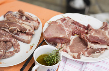 horizontal image of dishes with various types of raw meat ready to be cooked on the grill