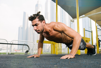 Obraz premium Young muscular arab athlete doing pushups otdoors in Dubai.