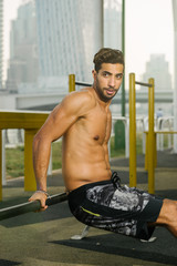 Obraz premium Young muscular arab athlete doing pushups on a horisontal bar otdoors in Dubai.
