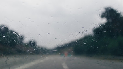 Water drops on a blurred rainy driving road 