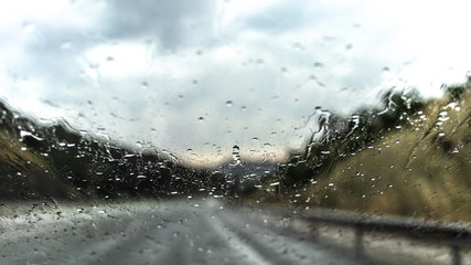 Water drops on a blurred rainy driving road 