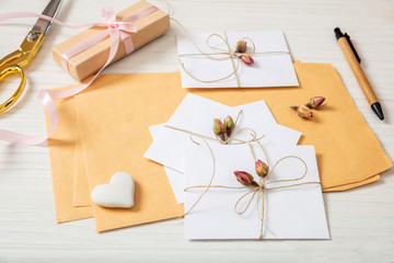 Flat lay of gift box and invitations on a white wooden tabletop, background.