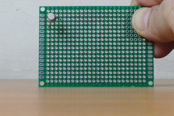 User holding a green protoboard with a transistor mounted