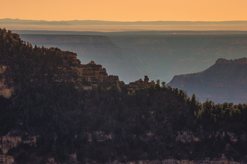 Sun setting below mountain peaks north side Grand Canyon