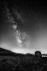 Beautiful view of starred night sky with milky way over a cultivated field with hay bale
