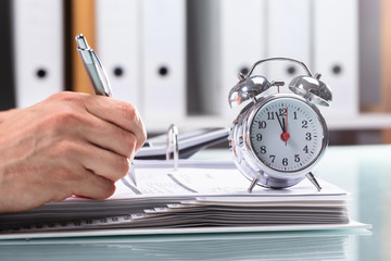 Businessman Working On Document With Alarm Over Desk