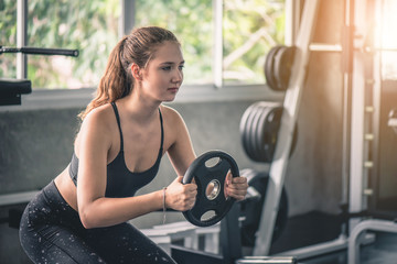 Fototapeta na wymiar Cinematic tone of young attractive fitness woman exercise with machine in gym. 