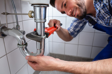 Plumber Repairing Sink In Bathroom