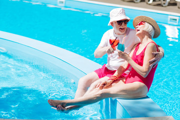 Laughing near pool. Retired beaming man and woman laughing out loud while sunbathing near pool