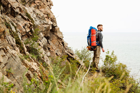 Young guy tourist with backpack on lake and mountains background