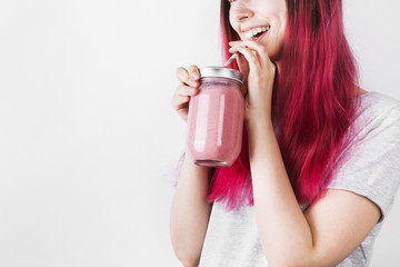 Young woman with pink hair drinks smoothies from berries and fruits. Concept meals to go. Copy space. Food background