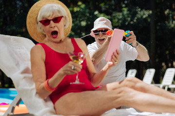 Laughing man. Laughing man wearing dark sunglasses sprinkling water on his surprised fashionable wife