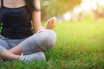 Young attractive Asian woman practicing yoga at the park in the morning. Healthy and lifestyle sport for relaxation by meditation with nature concept. 